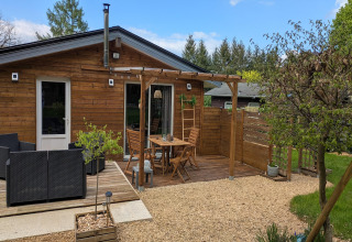 Houten terras met zithoek en pergola bij Chatillon 67 lodge in België, omgeven door tuin.