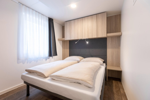 Moderne soveværelse med dobbeltseng, træskabe og naturligt lys i Chalets & Glamping Nassfeld 2, Østrig.