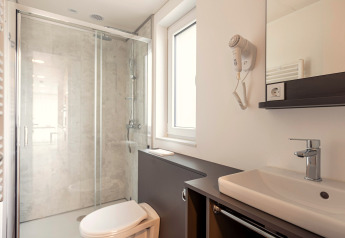 Moderne badkamer bij Chalets «& Glamping Nassfeld 2» in Oostenrijk met douche en wastafel.