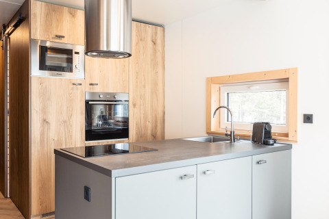 Moderne keuken in Chalets «& Glamping Nassfeld 3» in Oostenrijk met houten kasten en oven.