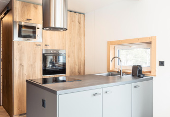 Cucina moderna degli Chalets «& Glamping Nassfeld 3» in Austria con armadi in legno e elettrodomestici.