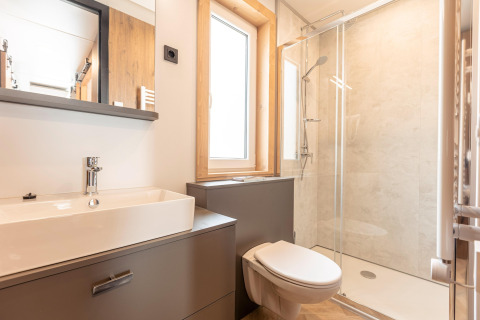 Moderne badkamer met hangend toilet, douche, wastafel, groot raam bij Chalets & Glamping Nassfeld 3 in Oostenrijk.