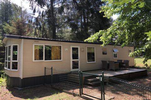 Lodge Bosuil dans la forêt, avec terrasse aménagée et mobilier extérieur, entouré de nature verdoyante.