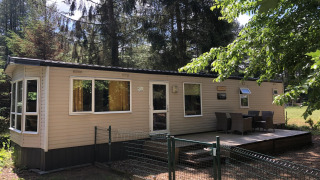 Lodge Bosuil immerso nel bosco con terrazza, tavolo da esterno e natura verde tutto intorno.