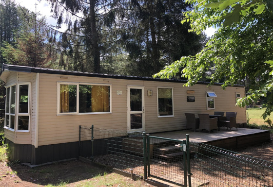 En hyggelig hytte kaldet Bosuil med en terrasse og havemøbler, omgivet af skov og grønne træer.