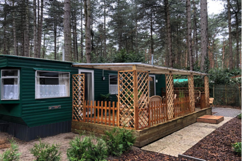 Chalet Specht immerso nel bosco, esterno verde, ampia finestra e veranda coperta con mobili in legno.