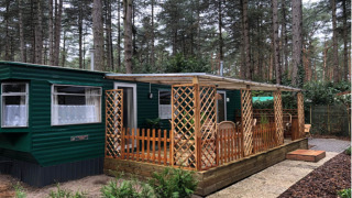 Chalet Specht immerso nel bosco, esterno verde, ampia finestra e veranda coperta con mobili in legno.