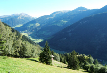 Foto vom Chalet Pirkach in Österreich, eingebettet in grüne Hügel und Täler mit Bergen im Hintergrund.