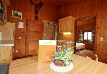 Innenraum vom Chalet «Pirkach» in Österreich mit Holzwänden, Esstisch und Blick ins Schlafzimmer.