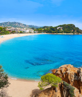 Hermosa bahía junto a un parque vacacional con glamping, arena dorada, agua azul y vegetación costera.