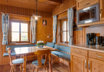 Gemütliche holzverkleidete Essecke in Chalet Pirkach, Österreich, mit blauen Sitzpolstern und Fenstern.