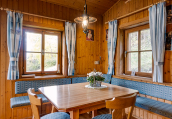 Gemütliche Essecke mit Holzverkleidung, blauen Polsterbänken und Fenstern, Chalet «Pirkach», Österreich.