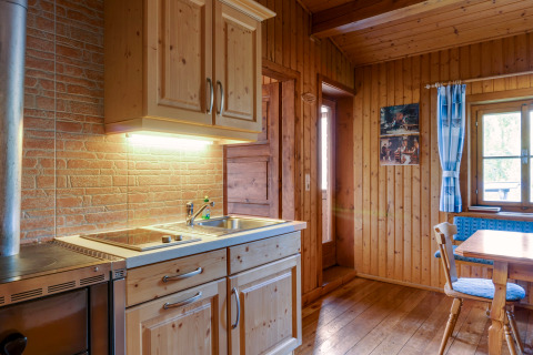 Et hyggeligt køkken i træ på Chalet Pirkach i Østrig, med spisebord og udsigt gennem vinduet.