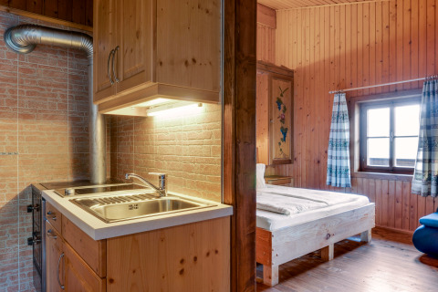 Indvendigt billede af Chalet «Pirkach» i Østrig, der viser et træbeklædt soveområde og et lille køkken.