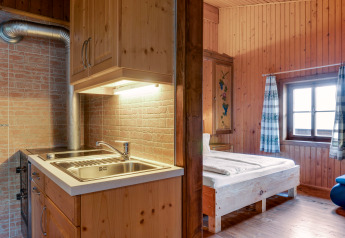Innenaufnahme des Chalets «Pirkach» in Österreich mit gemütlichem Schlafzimmer und kompakter Küche.