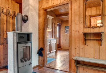 Holzverkleidetes Interieur im Chalet «Pirkach» in Österreich mit Kaminofen, Spiegel und Küche.