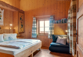 Soveværelse i Chalet Pirkach i Østrig med trævægge, seng, vindue og hyggelig læsehjørne
