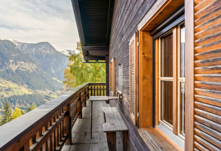 Træbalkon på Chalet «Pirkach» i Østrig med udsigt over bjergene og grøn dal i foråret