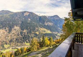 Blick von Chalet Pirkach in Österreich auf grüne Alpentäler, Wälder und schneebedeckte Gipfel.