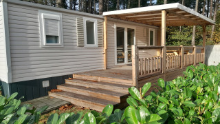 Casa vacanza a Verblijfpark Breebos 3 con veranda in legno coperta e piante verdi circostanti nel bosco.