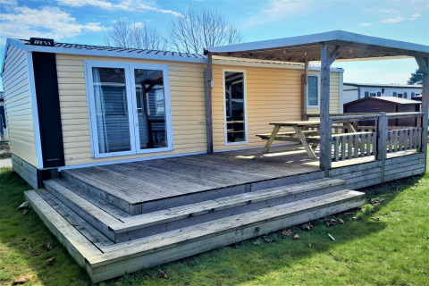 Buitenaanzicht van een houten lodge met terras en overkapping bij Verblijfpark Breebos 4.