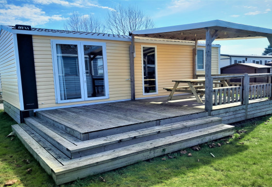 Buitenaanzicht van een houten lodge met terras en overkapping bij Verblijfpark Breebos 4.