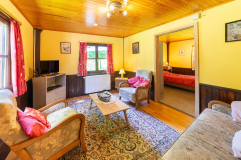Gezellige woonkamer in lodge «Les Bouleaux» in België, met klassieke stijl en zicht op de slaapkamer.