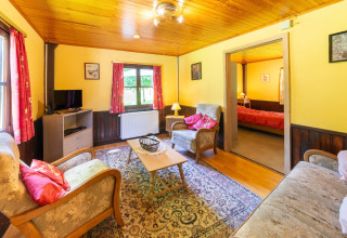 Gezellige woonkamer in lodge «Les Bouleaux» in België, met klassieke stijl en zicht op de slaapkamer.