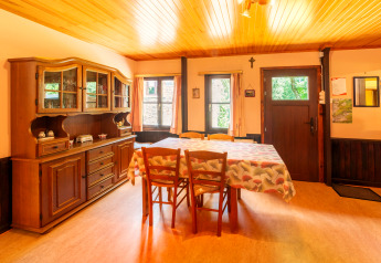 Dining room at lodge «Les Bouleaux» in Belgium with wooden furniture, china cabinet and tablecloth.