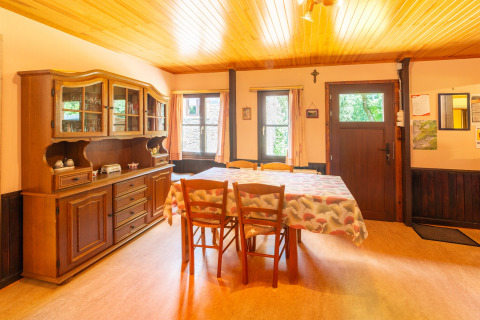 Eetkamer in lodge «Les Bouleaux» in België met houten meubels, vitrinekast en tafellaken.