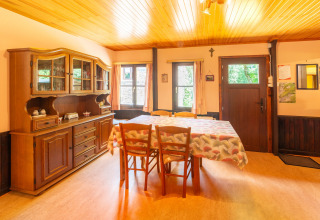 Eetkamer in lodge «Les Bouleaux» in België met houten meubels, vitrinekast en tafellaken.