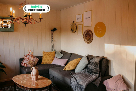 Gemütliches Wohnzimmer im Chalet Chocolat in Belgien mit Ecksofa, Kissen und stilvoller Wanddekoration.