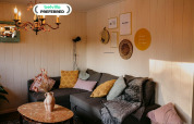 Acogedor salón en Chalet Chocolat, Bélgica, con sofá esquinero, cojines variados y decoración de pared.
