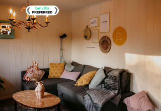 Gemütliches Wohnzimmer im Chalet Chocolat in Belgien mit Ecksofa, Kissen und stilvoller Wanddekoration.