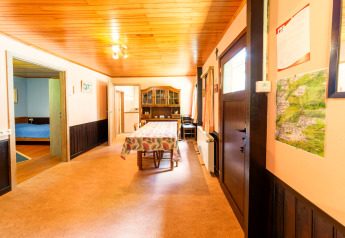 Dining area at lodge Les Bouleaux in Belgium, with wooden ceiling, table, wall map, and doorway to bedroom.