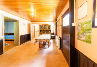 Eetkamer in lodge Les Bouleaux in België met houten plafond, tafel, kaart aan de muur en toegang tot slaapkamer.