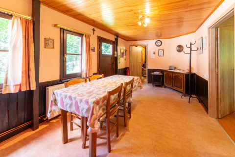 Eetkamer van lodge «Les Bouleaux» in België met houten meubels, ramen en een gezellige sfeer.