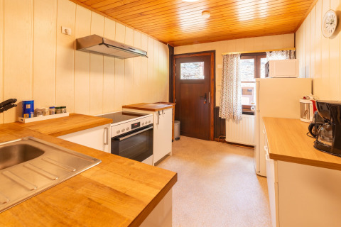 Lichte keuken met houten werkblad in lodge Les Bouleaux in België, met oven en koffiezetapparaat.
