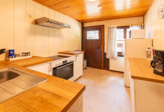 Lichte keuken met houten werkblad in lodge Les Bouleaux in België, met oven en koffiezetapparaat.