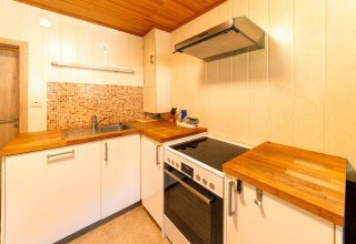 Moderne keuken met houten werkblad, fornuis en oven in de Les Bouleaux lodge, België.