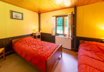Room at lodge 'Les Bouleaux' in Belgium featuring two single beds, yellow walls, and a wooden ceiling.