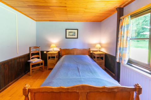 Sfeervolle slaapkamer in Les Bouleaux-lodge in België met eenpersoonsbed, houten meubelen en raam.