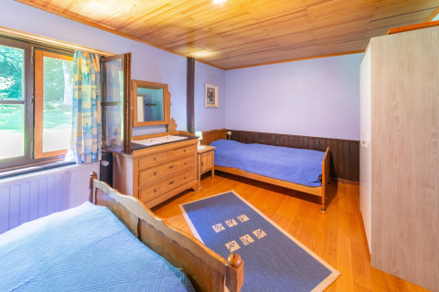Lichte slaapkamer in lodge Les Bouleaux in België, met twee bedden, houten meubels en groot raam.