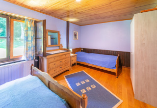 Lichte slaapkamer in lodge Les Bouleaux in België, met twee bedden, houten meubels en groot raam.