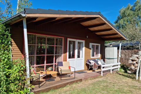 Acogedor chalet Casita La Luna con terraza de madera, asientos exteriores y vista al jardín.