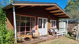 Sfeervol chalet Casita La Luna met houten terras, tuinmeubilair en stapel hout in de zon.