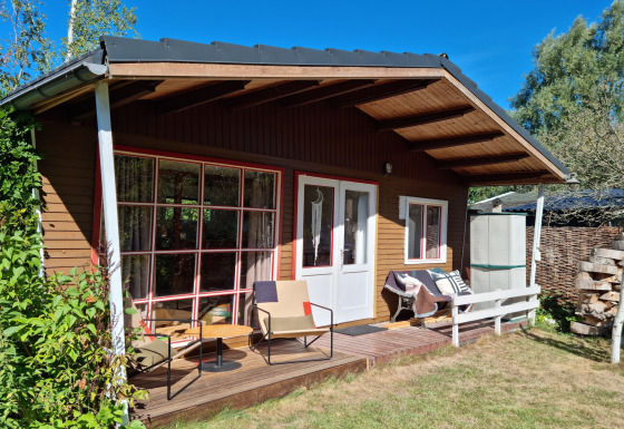 Acogedor chalet Casita La Luna con terraza de madera, asientos exteriores y vista al jardín.