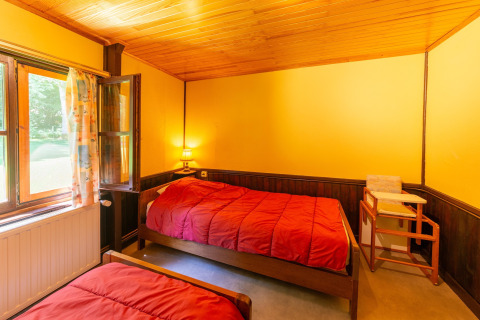 Gezellige kamer met twee eenpersoonsbedden, open raam en gele muren bij Les Bouleaux-lodge in België.