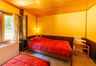 Gezellige kamer met twee eenpersoonsbedden, open raam en gele muren bij Les Bouleaux-lodge in België.