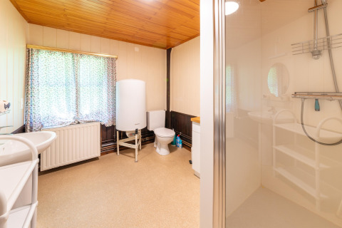 Lichte en ruime badkamer in lodge 'Les Bouleaux' in België met douche, toilet en groot raam.